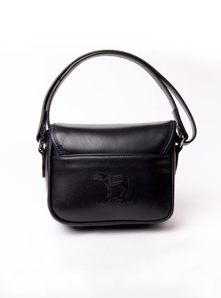 Flat lay of a small premium bridle butt navy leather crossbody Faith hand bag that has been hand stitched in England with 1 front facing buckle strap and the back embossed with Newmarket 875 horse logo.